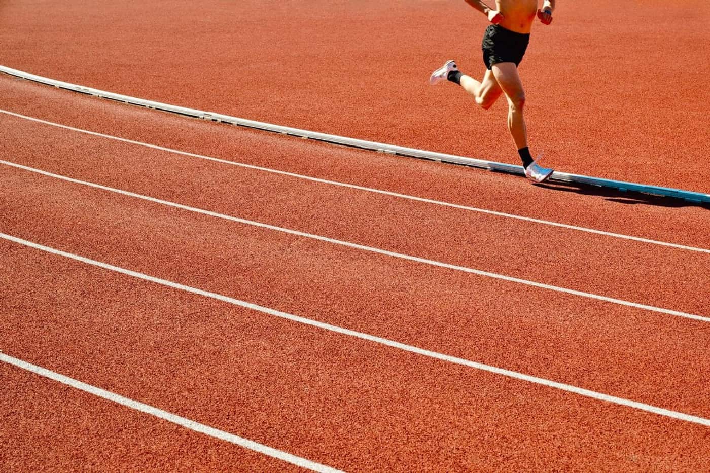 A runner mid-stride in the outside lane of a track